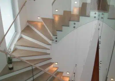 Beton-Stiege mit Holzstufen und Glasgeländer.