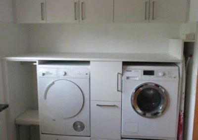 Waschküchenverbau mit eingebautem Trockner und Waschmaschine.