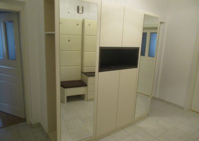 Creme farbenes Vorzimmer mit matter Oberfläche. Grifflose Ausführung mit TIP ON. Zwei offene Garderobenschränke mit Spiegelwand.