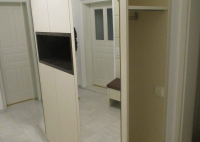 Creme farbenes Vorzimmer mit matter Oberfläche. Grifflose Ausführung mit TIP ON. Zwei offene Garderobenschränke mit Spiegelwand.