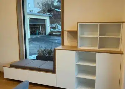 Sitzfenster mit braunem Sitzpolster aus Leder frontal mit weißem Wohnzimmerkasten / Verbau