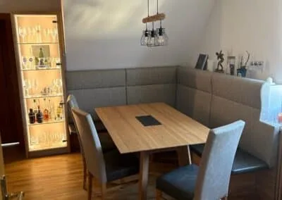 Esstisch mit Eckbank und grauen Polstern und drei Stühlen